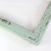 This textured frame features a distressed style and a desert-like finish. The face is a bright sea foam green with red-toned wood finish showing through the distressed surface.